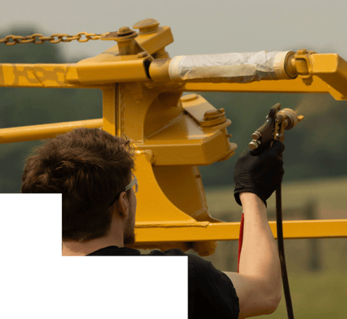 man applying yellow coating to equipment