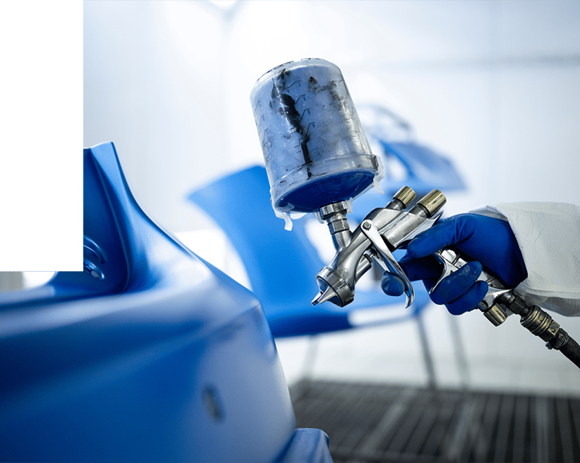 Gloved hand spray painting a blue vehicle