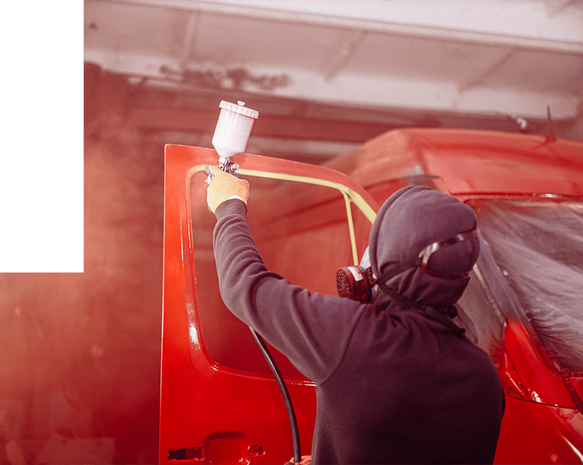 Worker spray painting red vehicle