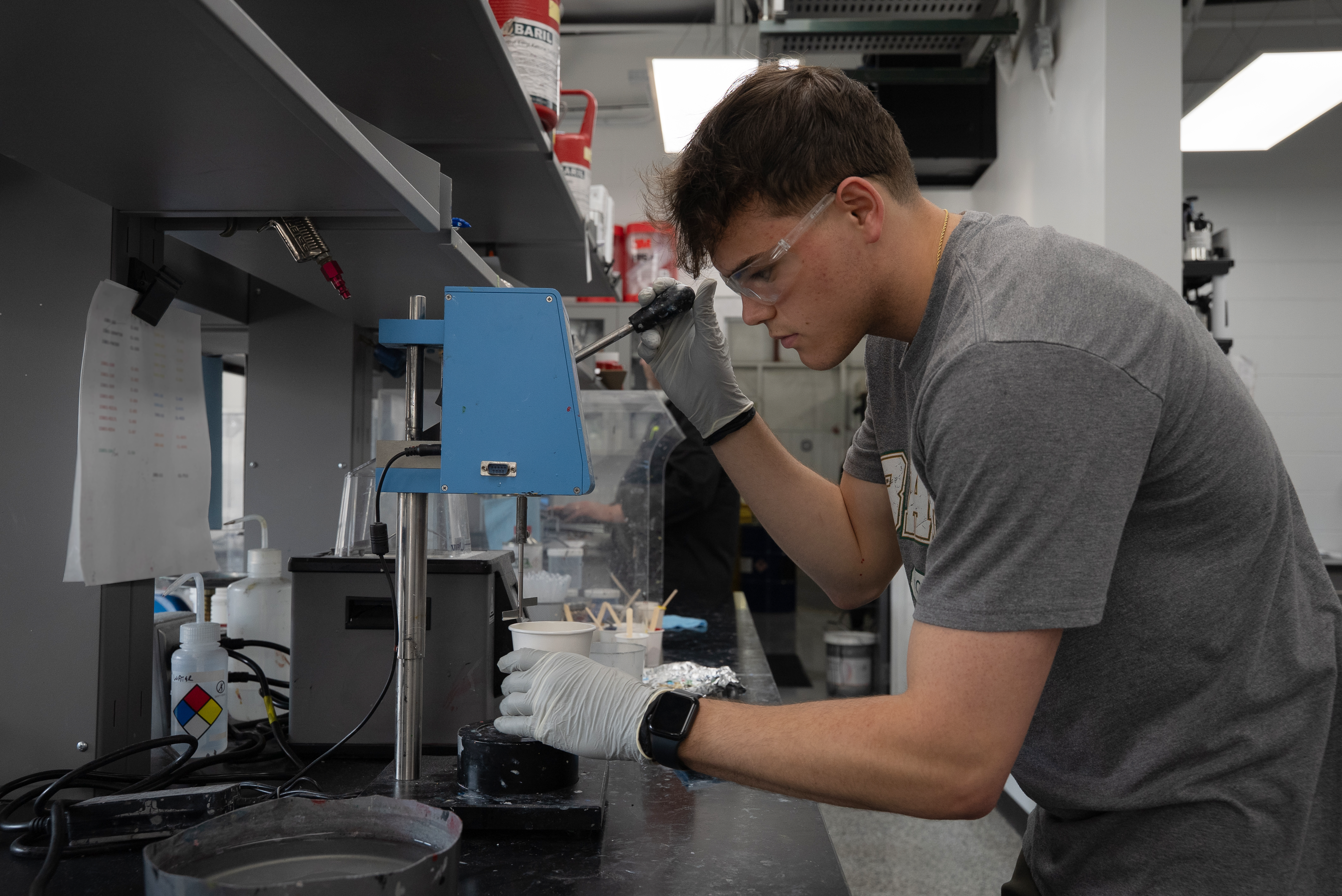 Man in PPE mixing paint in a lab