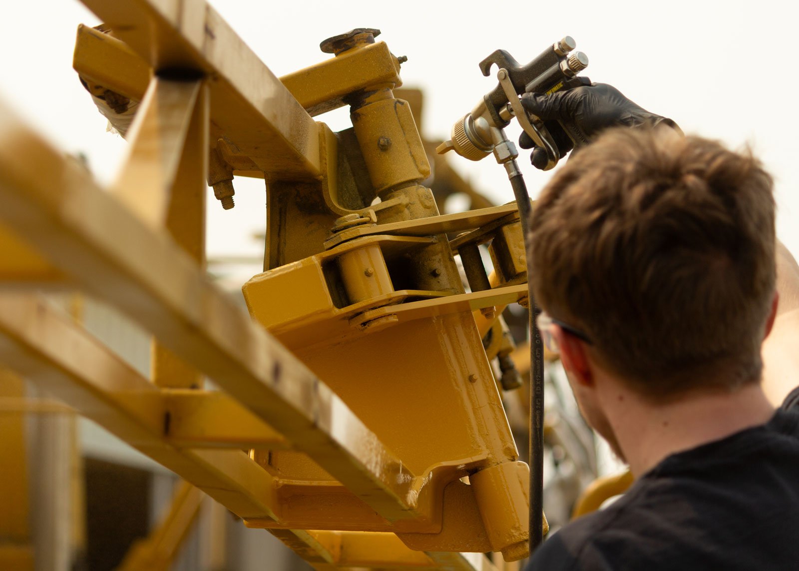 man spraying coating to machinery